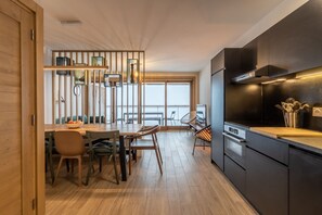 A modern kitchen with black cabinets, a wooden dining table, and a view to the outside.