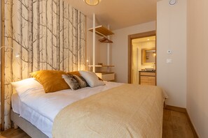 A bedroom with a large bed, a nightstand, a wardrobe, and a mirror.