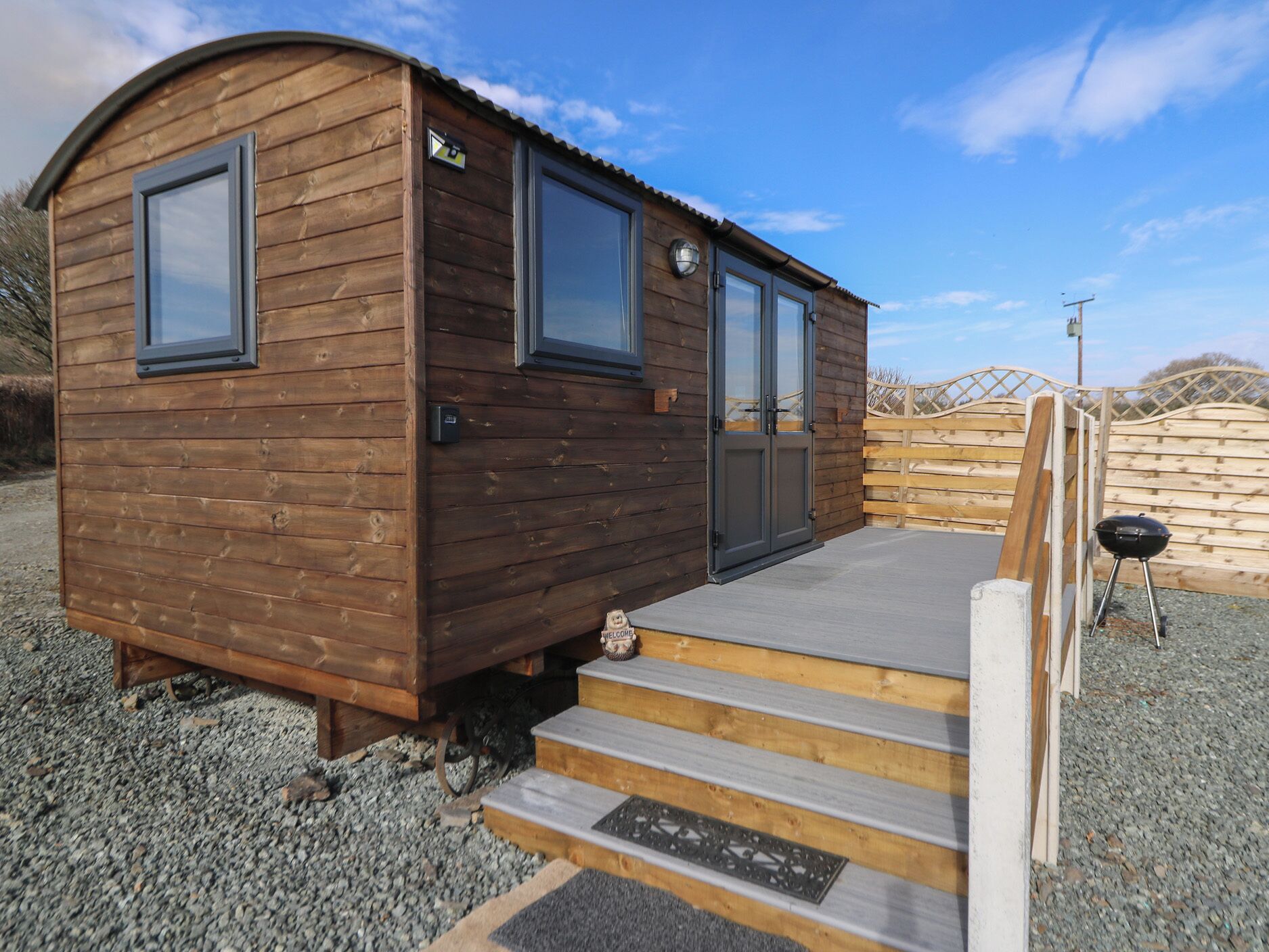 A small wooden cabin with a porch and steps leading up to a door.
