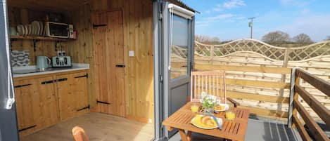 Un intérieur en bois avec une cuisine et un coin repas sur une terrasse.