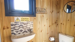 Un baño con paneles de madera, un lavabo, una señal de precaución y un inodoro.