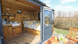 Una cabaña de madera acogedora con cama, kitchenette y comedor con desayuno.