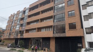 Um edifício de vários andares com fachada de tijolos, grandes janelas e entrada para garagem.