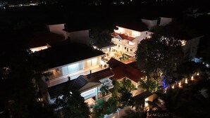 A multi-story building with a balcony and outdoor seating area, surrounded by trees and other buildings. - Casa Ahaana Resort Vagator, by Lavin Hotels (Vagator)
