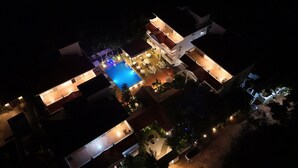 An aerial view of a hotel with multiple buildings connected by walkways, a central swimming pool, and outdoor seating areas. - Casa Ahaana Resort Vagator, by Lavin Hotels (Vagator)