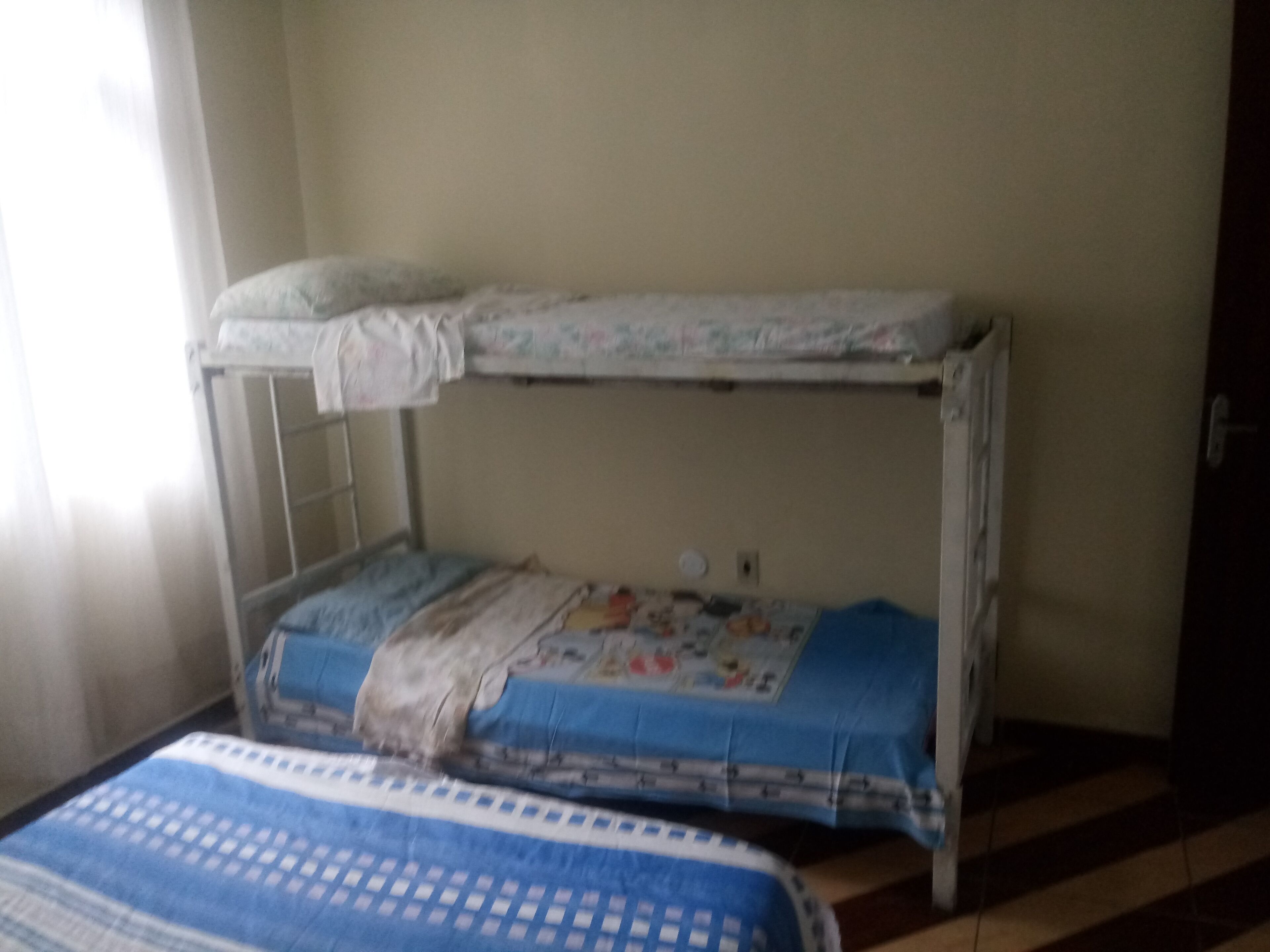 A bunk bed with a mattress on the top bunk and a lower bunk with a blue blanket.