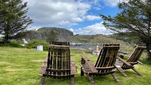 Two Adirondack chairs facing a scenic view of a lake and mountains. - Peaceful Island Cottage (Oban)