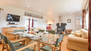 A dining area with a glass table, wooden chairs, and a sofa. - Peaceful Island Cottage (Oban)