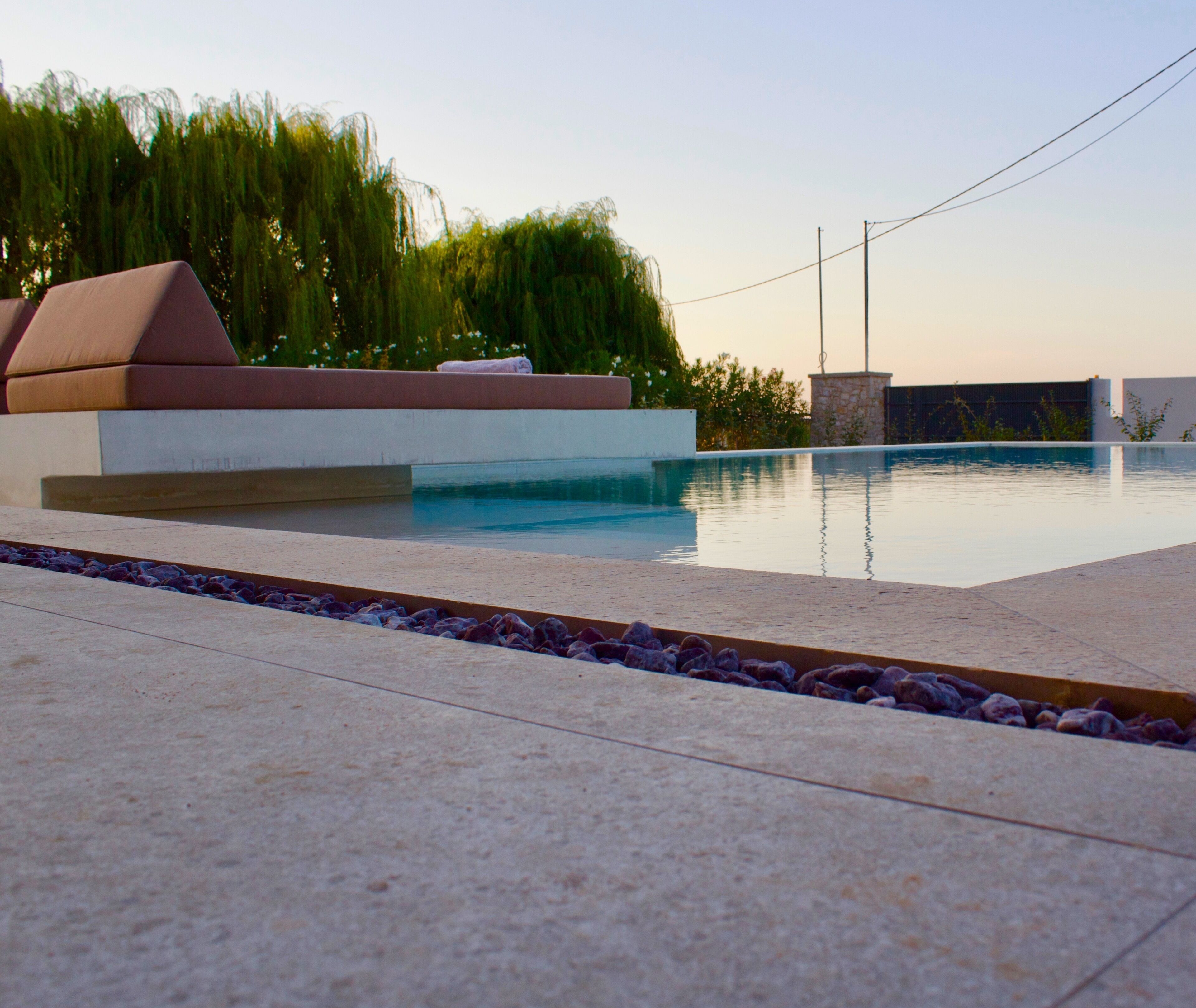 A swimming pool with a stone deck and a built-in seating area.