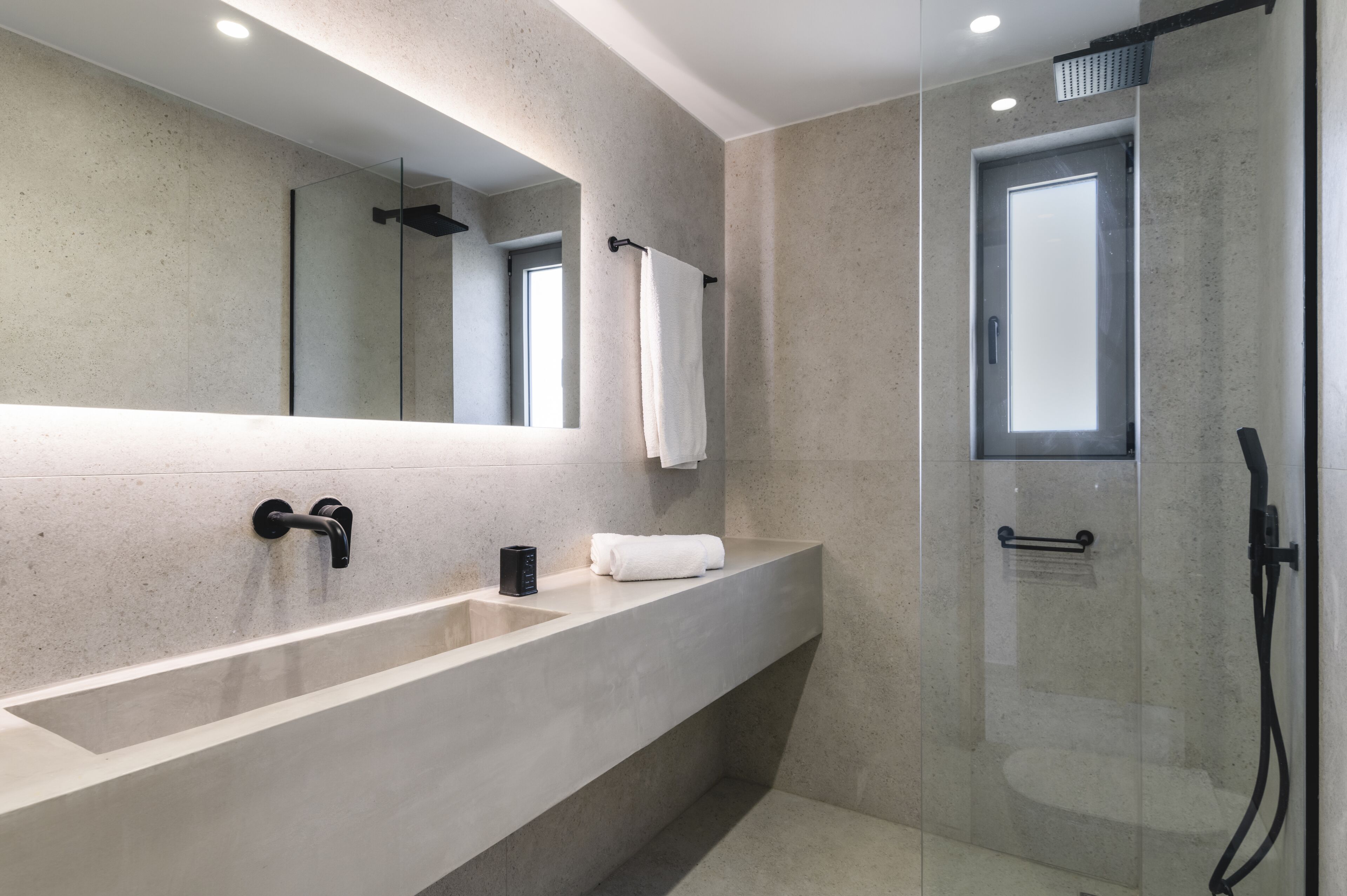 A modern bathroom with a large mirror, a bathtub, a shower, and a glass-enclosed shower area.