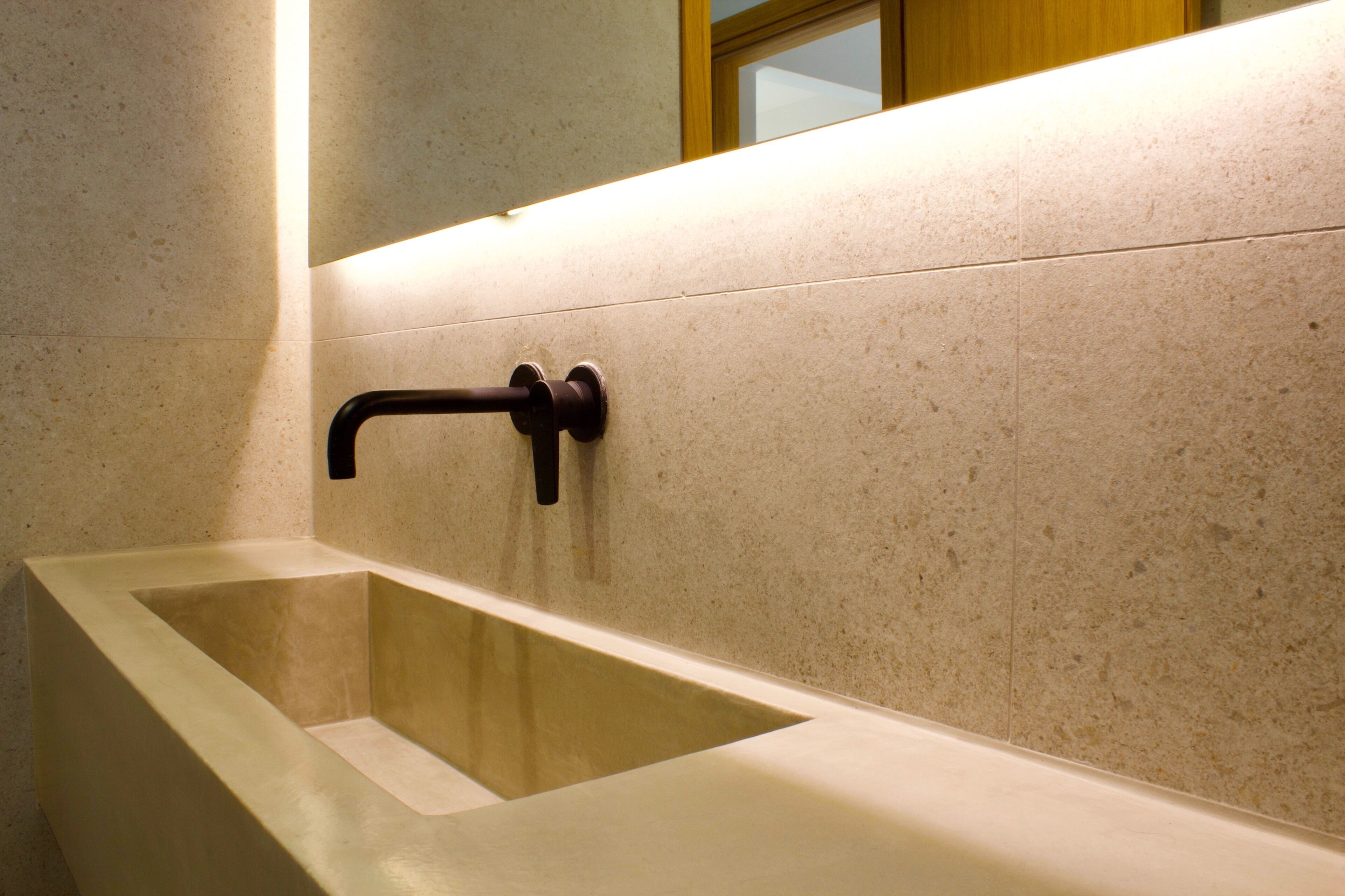 A modern bathroom with a rectangular bathtub, a wall-mounted faucet, and a mirror above the tub.