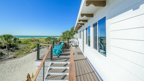 Een balkon met uitzicht op het strand, buitenmeubilair en een hekwerk.