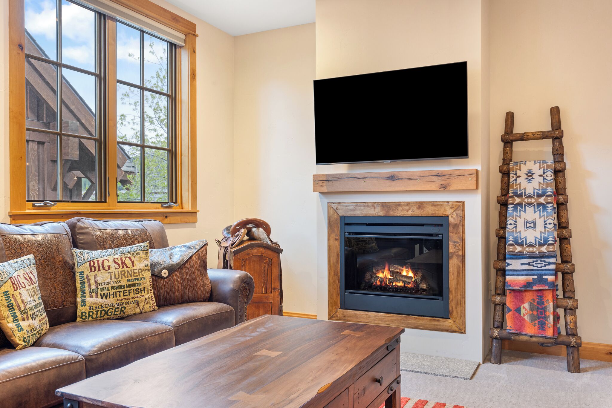 A living room with a leather sofa, a wooden coffee table, a fireplace, and a mounted TV.