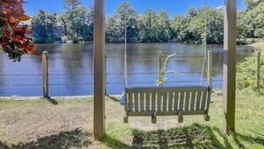 A wooden swing bench under a pergola by a lake with trees in the background. - Brigantine Quarters, Shipyard Plantation, Hilton Head 2 bed/2 bath condo (Hilton Head)