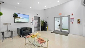 Un hall d’entrée moderne avec une table basse en verre, un canapé, un écran de télévision et un comptoir d’accueil.
