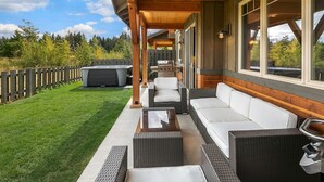 Eine Terrasse im Freien mit Korbmöbeln, einem Grill und einem Whirlpool.