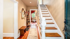 A staircase with wooden steps and white balusters, leading to a landing with a bench and a chair. - Enchanting Cottage, walk to Downtown Harpers Ferry (Harpers Ferry)