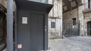 A narrow street with a closed grey door, a stone pavement, and a metal gate. - Casa Querida Central and Elegant Flat (Naples)