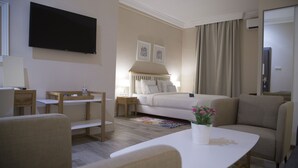 Une chambre d’hôtel avec un lit, un bureau, une chaise, une télévision et une petite table sur laquelle est posée une plante.