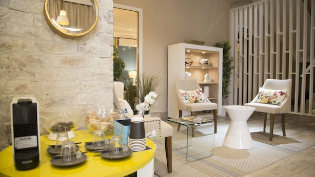 Un intérieur moderne avec une table jaune, des chaises blanches et une table basse en verre.