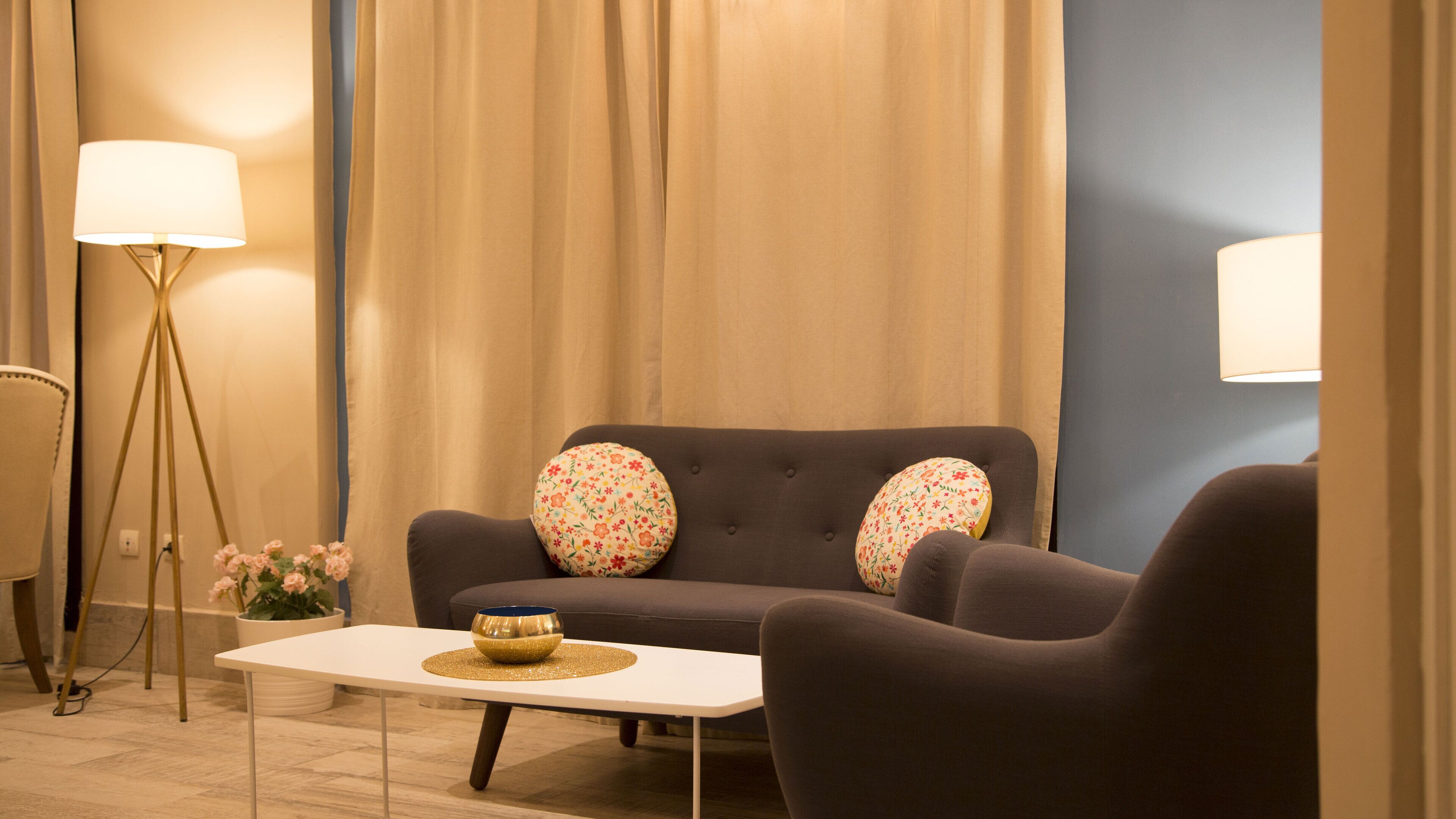 A modern living room with a sofa, two armchairs, a coffee table, and a floor lamp.