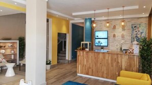 Un espace d’accueil avec un bureau en bois, un tapis bleu et un canapé jaune.
