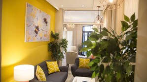 Un salon moderne avec un mur d’accent jaune, une grande peinture abstraite et un coin repas à l’arrière-plan.