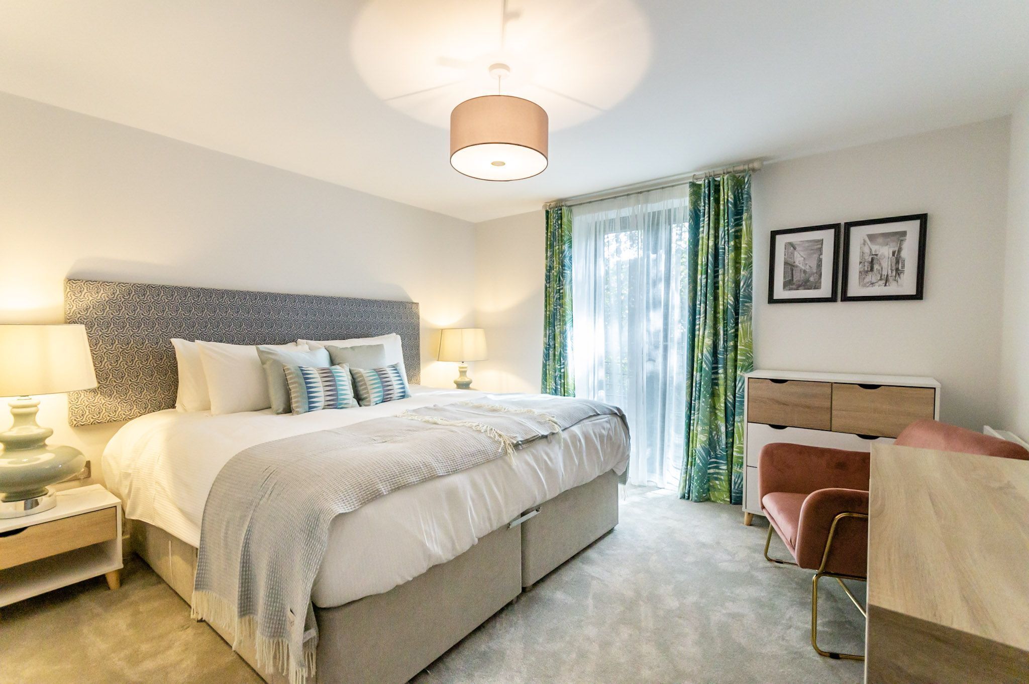 A modern bedroom with a large bed, bedside lamps, a dresser, and a chair.