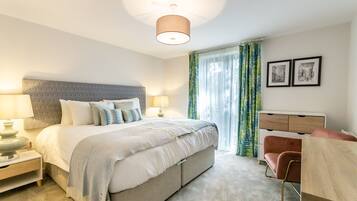 A modern bedroom with a large bed, bedside lamps, a dresser, and a chair.