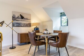 Un coin repas comprenant une table ronde, six chaises, une lampe, un buffet et un tableau accroché au mur.