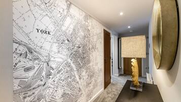 A hallway with a detailed map of New York City, a lamp, and a gold sculpture.