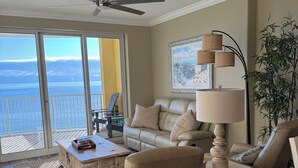 Ein geräumiges Wohnzimmer mit Meerblick, einem Deckenventilator, einer Couch, einem Couchtisch und einer Stehlampe.