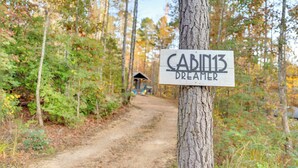 A sign for 'Cabin13 Dreamer' in a forested area with a dirt path leading to a small structure. - Serene, Hiking, Dreamer at Mentone Free Internet! (Mentone)