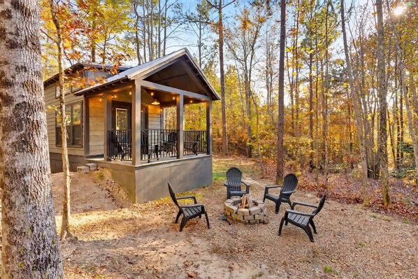 A cabin with a porch, outdoor seating, and a fire pit.