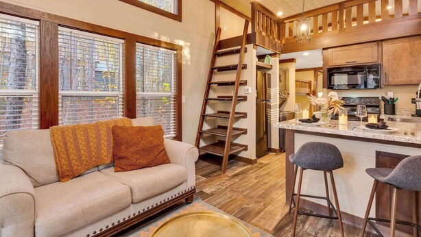 A cozy kitchen with a wooden staircase, a bar area, and a sofa with cushions. - Serene, Hiking, Dreamer at Mentone Free Internet! (Mentone)