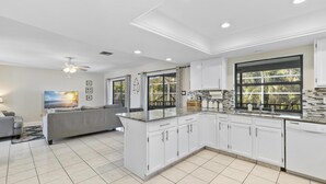 Una cocina moderna con armarios blancos, una isla grande y vistas al exterior.