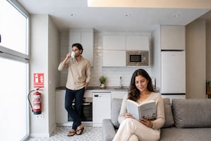 A modern kitchen with white cabinets, a microwave, and a fire extinguisher. - Port Suite X | 4 Guests  | AC & WiFi | 15 min Ciudad Artes (Valencia)