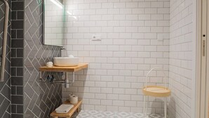 Ein Badezimmer mit einer weißen Duschkabine, einem Holzboden mit Waschbecken und einem kleinen Hocker.