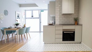 A modern kitchen with a built-in oven, a dining area with a table and chairs, and a view of the outside. - Port Suite III | 6 Guests | AC & WiFi | 15 min Ciudad Artes (Valencia)