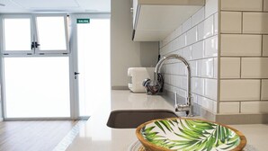 A modern kitchen with a sink, a bowl on the counter, and a door labeled "SALIDA". - Port Suite III | 6 Guests | AC & WiFi | 15 min Ciudad Artes (Valencia)