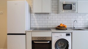 A compact kitchen with a refrigerator, microwave, oven, and washing machine. - Port Suite II | 4 Guests | AC & WiFi | 15 min Ciudad Artes (Valencia)