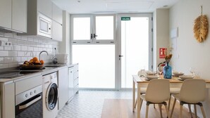 A modern kitchen with a washing machine, a sink, and a dining area with a table and chairs. - Port Suite II | 4 Guests | AC & WiFi | 15 min Ciudad Artes (Valencia)