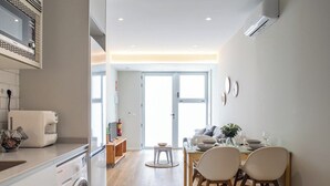 Een moderne keuken met een inbouwmagnetron, een wasmachine en een eethoek met tafel en stoelen.
