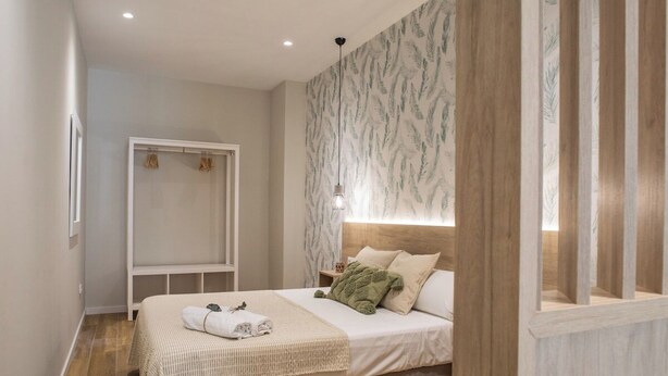 Een slaapkamer met een bed, nachtkastje, hanglamp en een kledingkast.