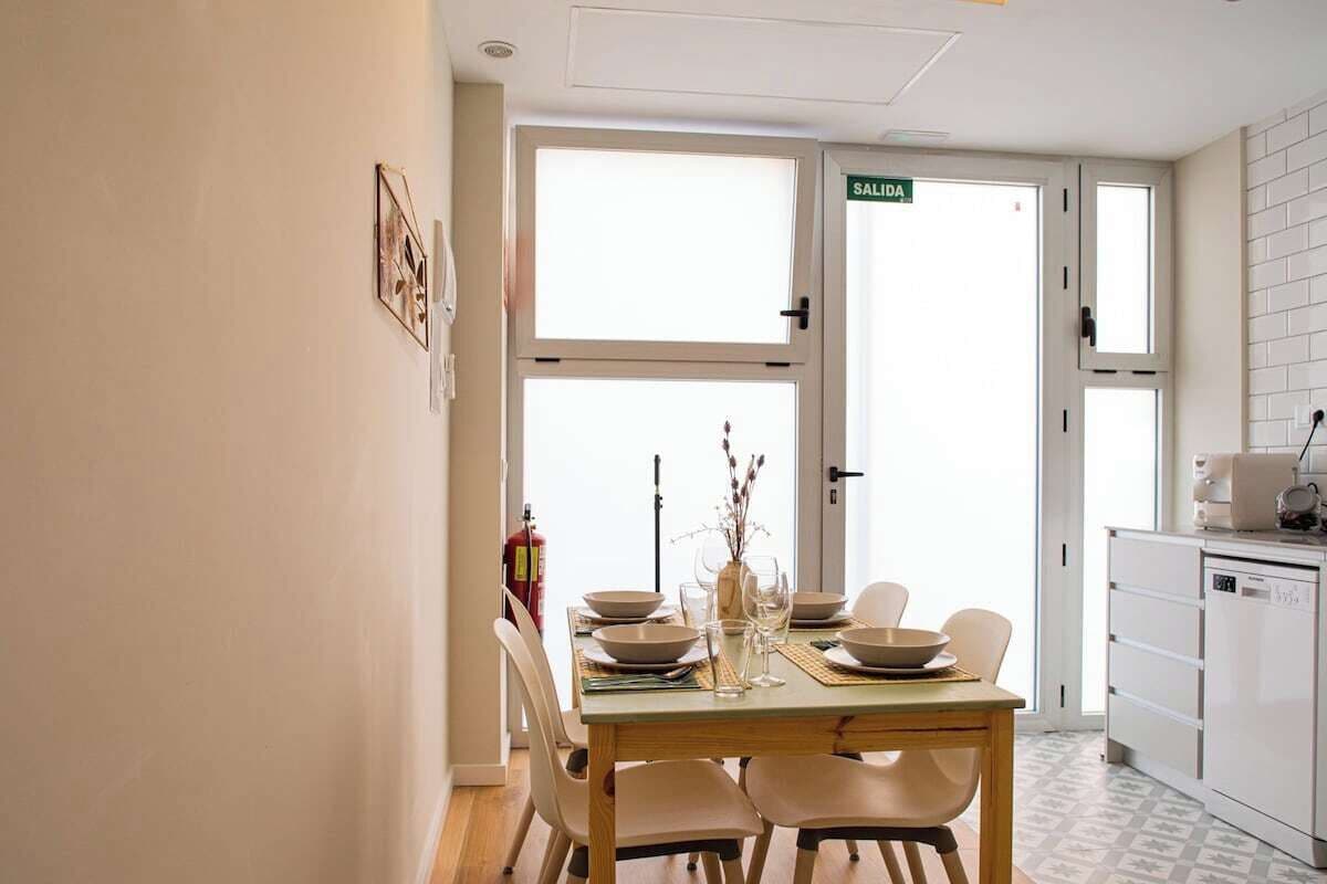 Een eethoek met een tafel voor vier personen, een keuken met een vaatwasser, en een deur met de aanduiding 