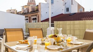 Mesa de desayuno al aire libre con vistas a edificios en el fondo.