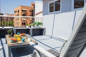 Ein Balkon mit Frühstückstisch, Topfpflanzen und Blick auf umliegende Gebäude.