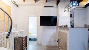 Una cocina moderna con televisor de pantalla plana, una barra y una escalera de madera.