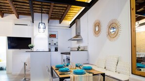 Cocina moderna con comedor, techo de madera, televisor de pantalla plana y espejos decorativos en las paredes.