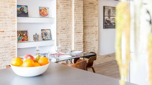 A modern dining area with a brick wall, a glass table, and a bowl of fruit. - CENTER-Luxurious 1BR, 1BA-Terrace, WI-FI, A/C (Valencia)